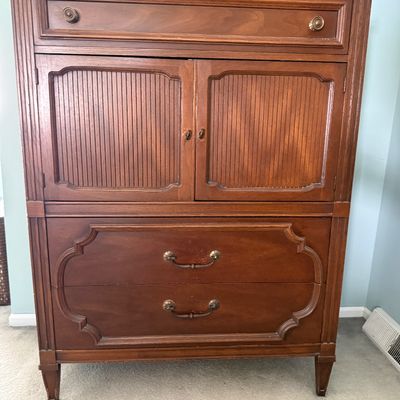 Vintage mid-century tall wood armoire dresser featuring dual cabinet doors with ribbed panel accents over two lower drawers.