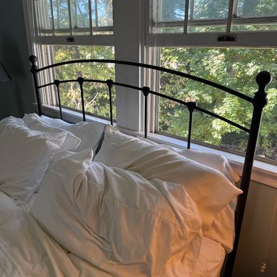 Black tubular metal arched headboard set against a double window, topped with finials.