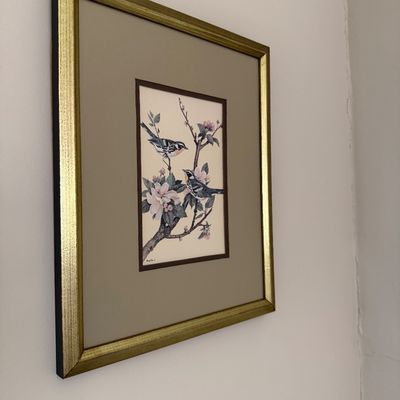 Framed botanical bird illustration featuring two songbirds perched on flowering branches, housed in a double-matted gilt wood frame.