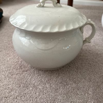 Antique white ironstone chamber pot with matching lid, featuring molded decorative details along the rim and side.