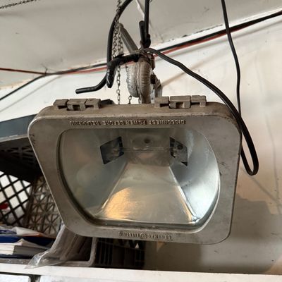Vintage General Electric metal floodlight fixture suspended from a chain mount with visible wiring and minor surface wear.