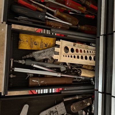 Open toolbox drawers filled with assorted hand tools, including screwdrivers, air fittings, drill gauge, pocket knife, and hardware...