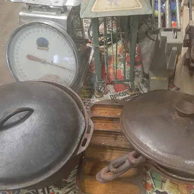 Assortment of vintage items including cast iron cookware, a cornbread stick pan, a commercial dial scale, and a painted pagoda-style...