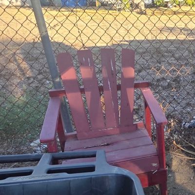 Sale Photo Thumbnail #39: Red painted wooden Adirondack chair with slatted back and wide armrests, showing weathering and paint wear from outdoor use.