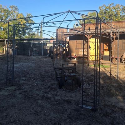 Sale Photo Thumbnail #46: Large wrought iron outdoor gazebo frame with decorative leaf accents.