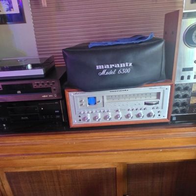 Sale Photo Thumbnail #50: Vintage audio equipment setup featuring a Marantz stereophonic receiver, a Marantz Model 6300 turntable with a black dust cover, and a reel-to-reel tape deck on a wooden cabinet.