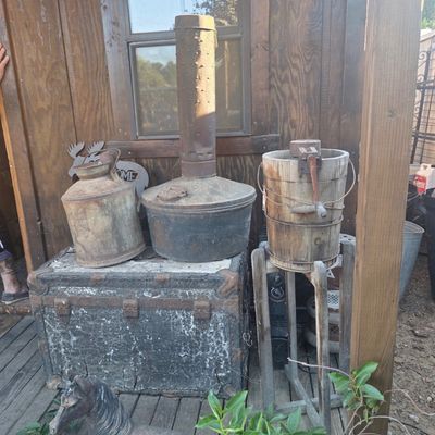 Sale Photo Thumbnail #61: Rustic rustic outdoor items including an antique orchard smudge pot, hand-crank ice cream maker, metal milk can, and weathered trunk.