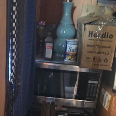 Sale Photo Thumbnail #65: A light blue ceramic table lamp base alongside a microwave, compact refrigerator, and assorted household goods.