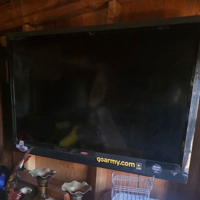 Sale Photo Thumbnail #69: Wall-mounted Vizio flat-screen television with black bezel and promotional stickers along the bottom edge.