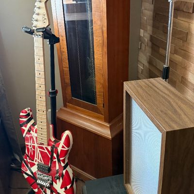 Sale Photo Thumbnail #79: EVH Frankenstein electric guitar on a stand alongside a wooden grandfather clock and a vintage RCA microphone.