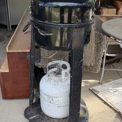 Sale Photo Thumbnail #85: Vintage black kettle-style outdoor propane grill with attached base and white propane tank, showing weathering and cobwebs from outdoor use.
