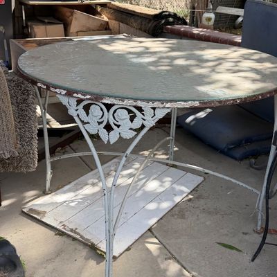 Sale Photo Thumbnail #86: Vintage round wrought iron patio table with a glass top, featuring painted floral rose details along the apron.