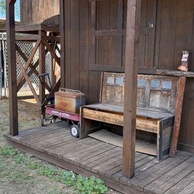 Sale Photo Thumbnail #91: Rustic wooden bench alongside a vintage red Radio Flyer wagon holding an antique metal metal cooler, displayed on a wooden porch exterior.