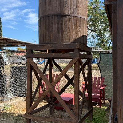 Sale Photo Thumbnail #92: Rustic wooden water tower structure featuring a cylindrical stave tank mounted on an elevated timber frame platform.