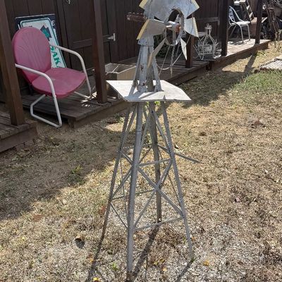 Sale Photo Thumbnail #94: Vintage metal decorative backyard windmill lawn sculpture featuring a weathered galvanized finish and yellow-tipped blades.