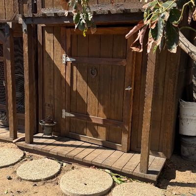 Sale Photo Thumbnail #107: Rustic wooden outdoor shed or playhouse styled like a Western saloon, complete with a porch decking, horseshoe detail, and vintage lantern accents.