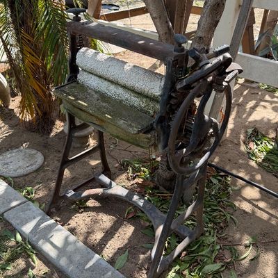 Sale Photo Thumbnail #110: Antique hand-crank clothes wringer machine featuring cast iron legs and weathered rollers, suitable for garden or rustic decor.