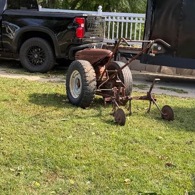 Sale Photo Thumbnail #129: Vintage walk-behind two-wheel tractor with a cultivator attachment, showing heavy patina and rust.