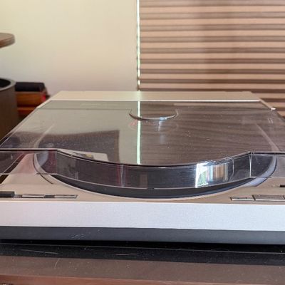 Sale Photo Thumbnail #135: Vintage silver and black turntable with a smoked dust cover, flanked by boxed Funko Pop figurines.