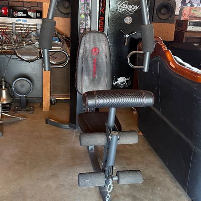 Sale Photo Thumbnail #138: Marcy multi-function home gym system featuring a padded seat with carbon fiber-style vinyl trim, press arms, and a leg developer attachment.