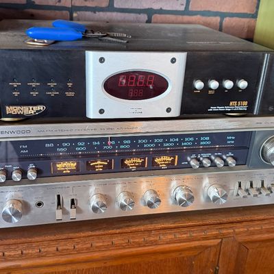 Sale Photo Thumbnail #147: Monster Power HTS 5100 Home Theatre Reference PowerCenter stacked on a vintage silver-face Kenwood AM/FM stereo receiver, both sitting atop a carved wooden cabinet.