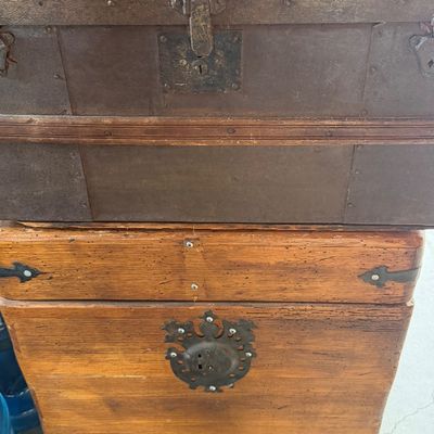 Sale Photo Thumbnail #148: Stack of two antique trunks, including a top dome-top steamer trunk with metal strapping and a bottom rustic wooden trunk with ornate iron escutcheon hardware.
