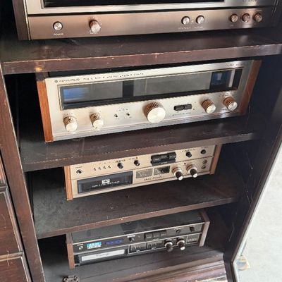 Sale Photo Thumbnail #149: Vintage stereo components including Kenwood solid-state AM-FM stereo tuners and Akai cassette tape decks housed inside a wooden hifi cabinet.