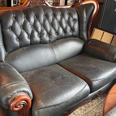 Sale Photo Thumbnail #151: Vintage black leather loveseat featuring a button-tufted high back, carved wood trim, and scroll arms.