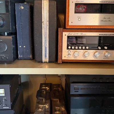 Sale Photo Thumbnail #156: Collection of vintage audio equipment on metal shelving, including a Marantz Model 105 tuner, a Marantz Model 4230 receiver, Yamaha components, and various hard carrying cases.