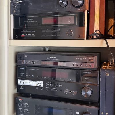 Sale Photo Thumbnail #157: Collection of vintage audio and video components, including a McIntosh MR7082 tuner, Sony receiver, Toshiba DVD player, Yamaha receiver, and Adcom preamplifier stacked on metal shelving.