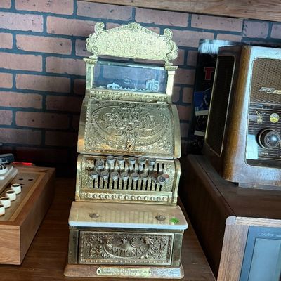 Sale Photo Thumbnail #160: Antique National ornate brass cash register with top sign header, white marble shelf, and detailed scrollwork casing.