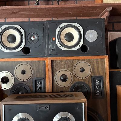 Sale Photo Thumbnail #169: Collection of vintage stereo speakers, featuring black JBL studio monitors and wood-cased Marantz speakers with visible drivers and control knobs.