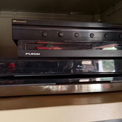 Sale Photo Thumbnail #170: Stack of home audio and video equipment, including Blu-ray players by Funai, LG, and Samsung alongside a Russound speaker selector switch.