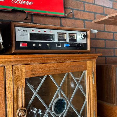 Sale Photo Thumbnail #177: Vintage Sony TC-228 8-track stereo tape deck with wood cabinet sitting atop a cabinet beside a Pioneer stereo receiver.