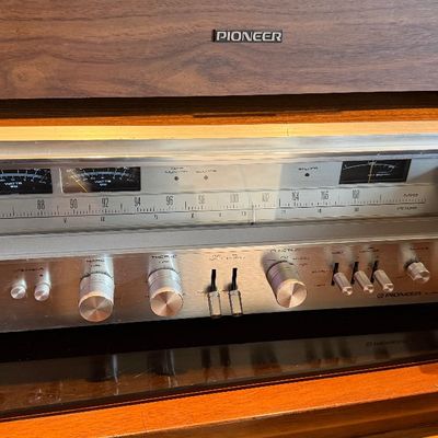 Sale Photo Thumbnail #197: Vintage Pioneer stereo receiver with a brushed aluminum faceplate, illuminated analog tuning display, and a wood grain cabinet, circa late 1970s.