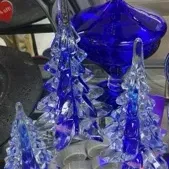 Sale Photo Thumbnail #26: Collection of cobalt blue and clear art glass items, featuring three decorative Christmas tree figurines and a footed candy dish with a lid.