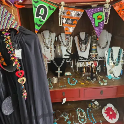 Sale Photo Thumbnail #58: Collection of assorted costume and turquoise jewelry displayed on busts inside a red cabinet decorated with Halloween pennants.