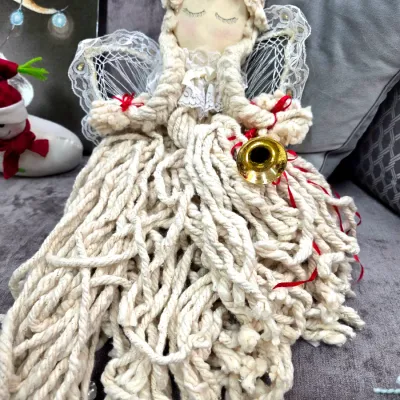 Sale Photo Thumbnail #65: Handmade mop yarn angel tree topper or doll featuring lace wings, embroidered eyes, and a small gold horn, circa late 20th century.