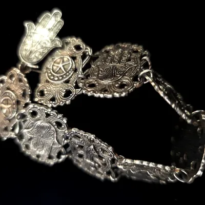 Sale Photo Thumbnail #79: Intricate silver-tone link bracelet featuring Hamsa hand and star-and-crescent motifs with openwork filigree details.