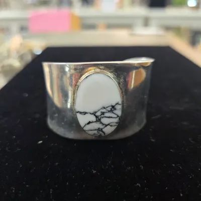 Sale Photo Thumbnail #81: Southwestern-style wide sterling silver cuff bracelet featuring an oval white buffalo stone cabochon set in a smooth bezel.