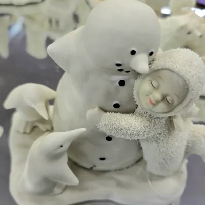 Sale Photo Thumbnail #85: Department 56 Snowbabies porcelain figurine featuring a snowbaby hugging a snowman surrounded by penguins, in excellent condition.