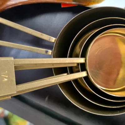 Sale Photo Thumbnail #86: Set of four vintage brass nesting measuring cups with looped handles.