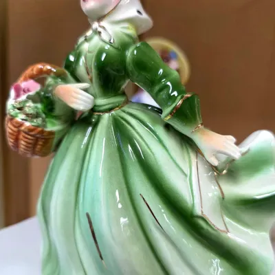 Sale Photo Thumbnail #154: Vintage Josef Originals ceramic figurine depicting a woman carrying a flower basket in a flowing green gown with gold accents.