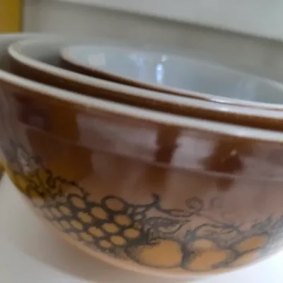 Sale Photo Thumbnail #191: Vintage Pyrex Autumn Harvest nesting mixing bowl set featuring a brown gradient with fruit and floral graphics.