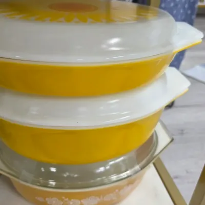 Sale Photo Thumbnail #213: Stack of vintage Pyrex casserole dishes in yellow and orange patterns with glass lids, circa 1970s.