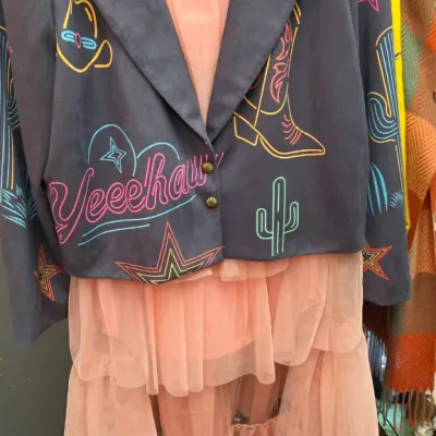 Sale Photo Thumbnail #279: Lucky & Blessed western-style jacket featuring neon embroidered graphics, layered over a coral pink ruffled tulle dress.