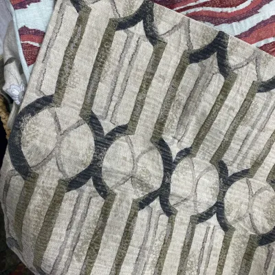 Sale Photo Thumbnail #301: Stack of patterned upholstery fabric swatches, featuring a beige and olive geometric velvet cut fabric on top.