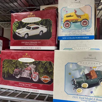 Sale Photo Thumbnail #322: Stack of vintage boxed Hallmark Keepsake Christmas ornaments featuring classic vehicles, including a 1969 Hurst Oldsmobile, Harley-Davidson Heritage Springer, and 1931 Ford Model A Roadster.