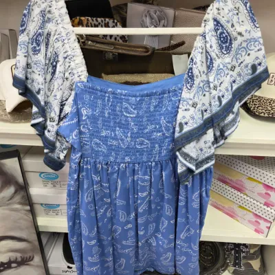 Sale Photo Thumbnail #357: Blue and white paisley print off-the-shoulder blouse with a smocked bodice and flutter sleeves, hanging on a white clothes hanger.