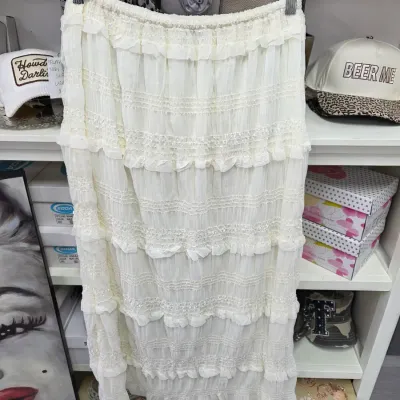 Sale Photo Thumbnail #367: Off-white tiered ruffle midi skirt with elastic smocked waist and delicate lace trim detail, displayed on a hanger in a closet setting.